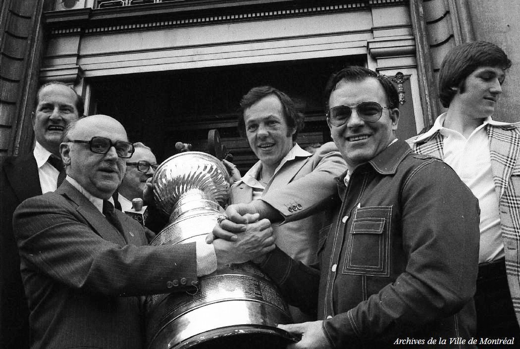 Le maire de Montréal Jean Drapeau, Yvan Cournoyer, Scotty Bowman, Murray Wilson et la coupe Stanley devant l'hôtel de ville de Montréal Le maire de Montréal Jean Drapeau, Yvan Cournoyer, Scotty Bowman, Murray Wilson et la coupe Stanley devant l'hôtel de ville de Montréal