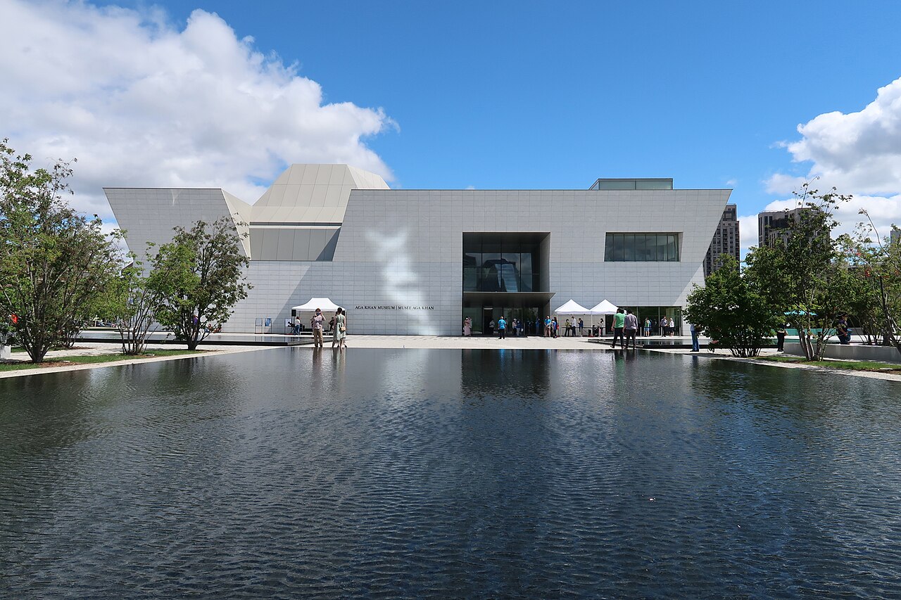 Aga Khan Museum A white museum building with a large water pond in front.
