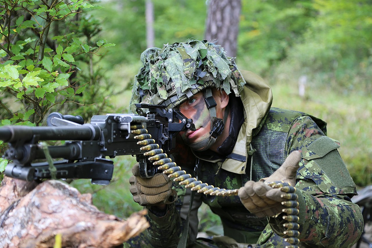 Un soldat du PPCLI avec une mitrailleuse polyvalente C6 Un soldat canadien vise une mitrailleuse polyvalente C6 tout en tenant une bande de munitions.