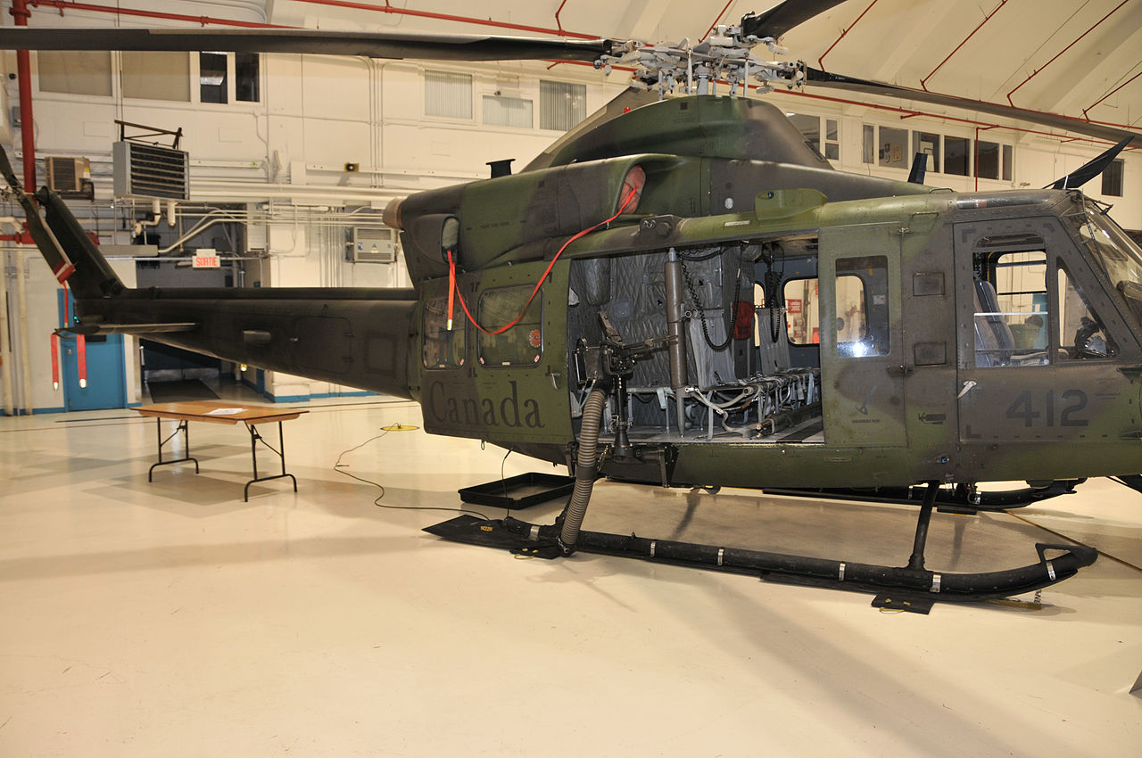 Un hélicoptère CH-146 Helicopter avec une C6 Un hélicoptère peint en vert et noir à l'intérieur d'un bâtiment