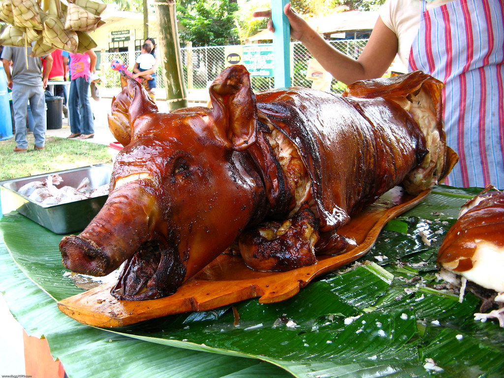 An entire roaster pig on top of some large leaves.
