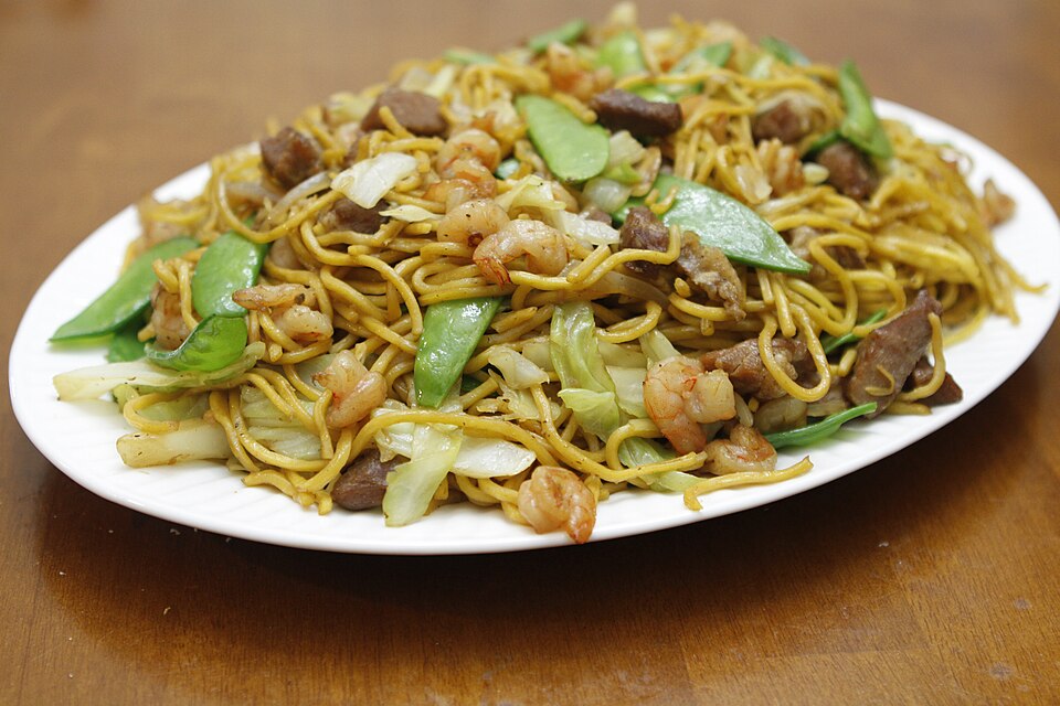 A plate of stir-fried noodles with vegetables, meat and shrimp.