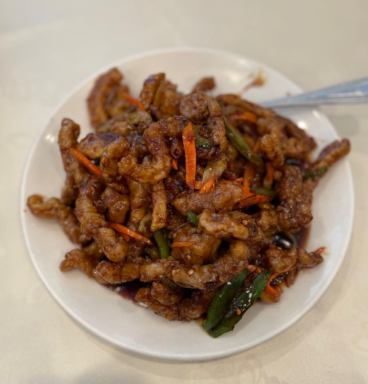 A plate of ginger beef on a white plate.