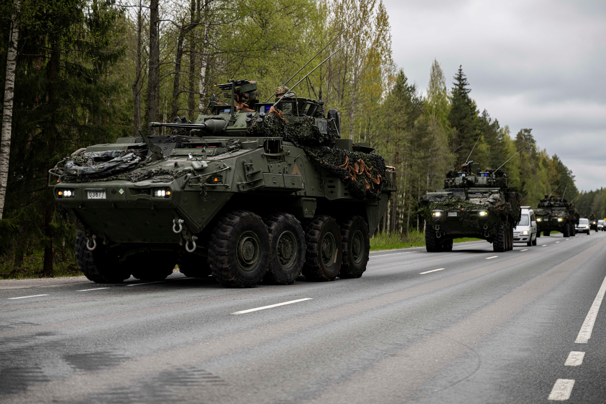 LAV 6.0 Column of vehicles with some cars on a forested highway.