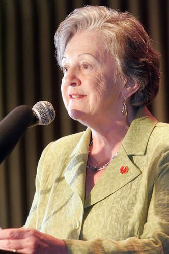 A woman with a green blazer at a microphone.