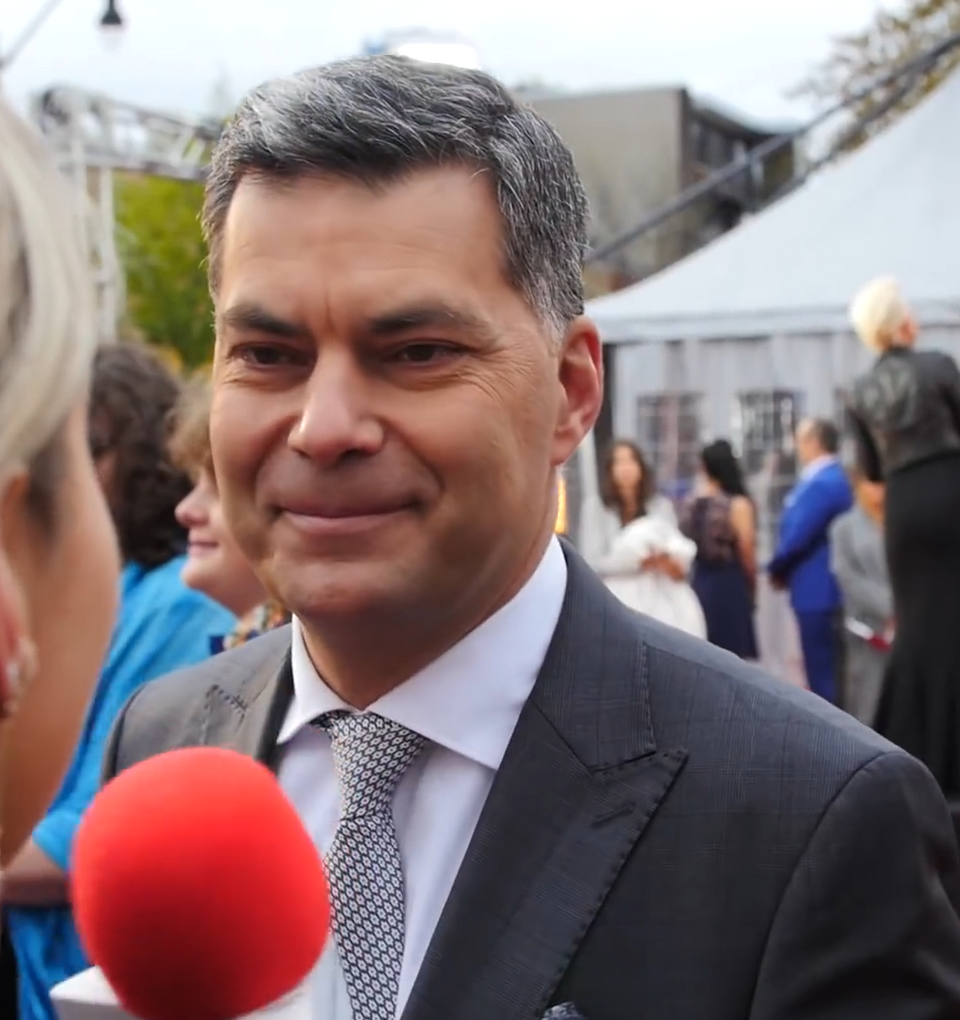 Mario Dumont, 2017 Man smilling at a person holding a red microphone.