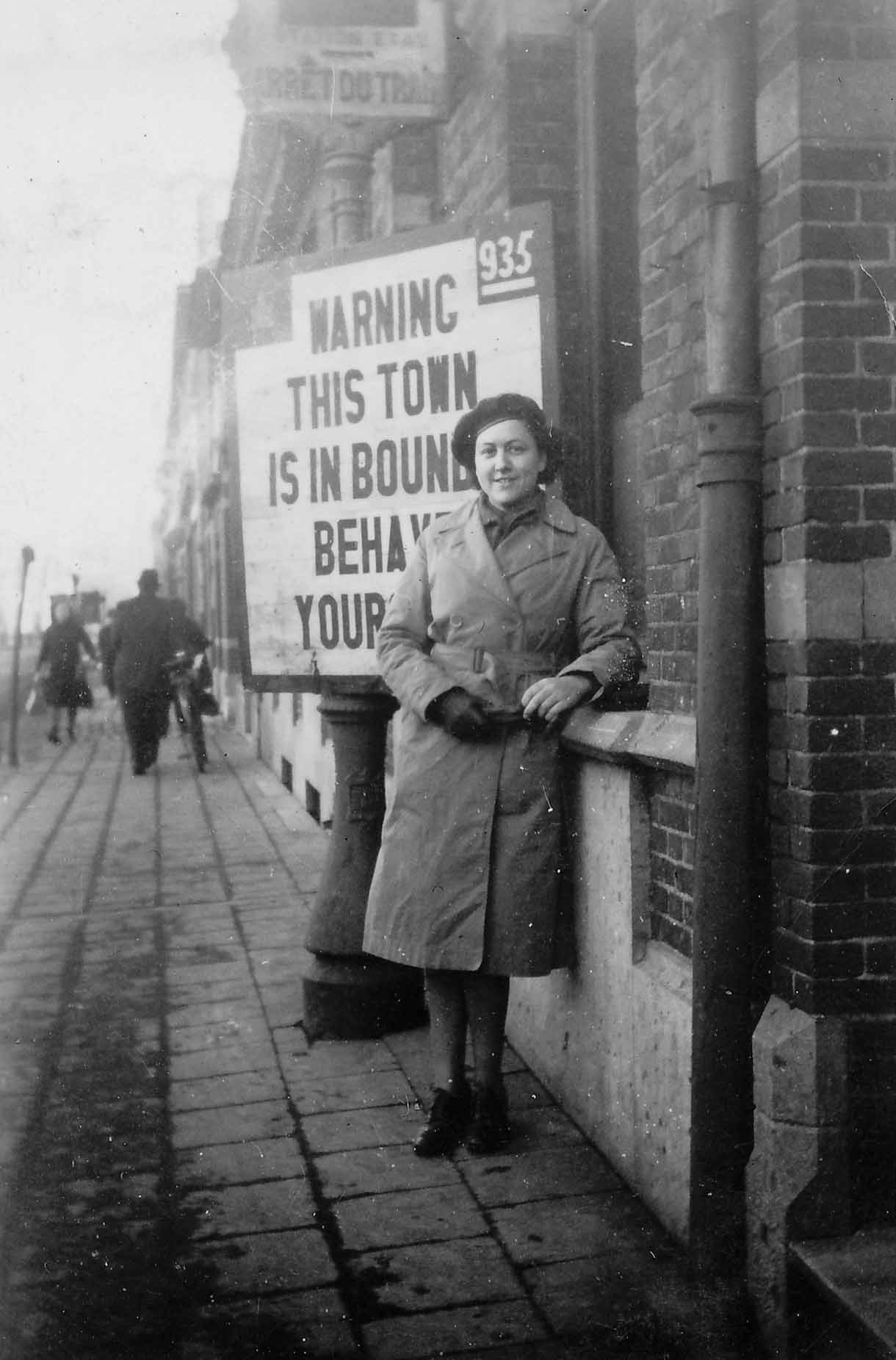 Bertha Hull (née Herr) standing in front of one of the typical Canadian signs in Belgium, February 1945.