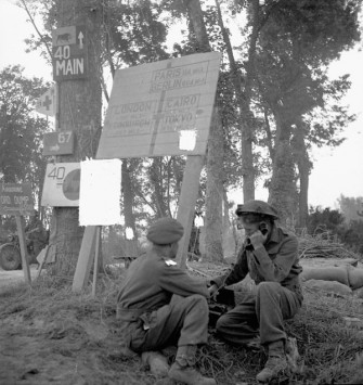 Personnel du Corps royal des transmission de l'Armée canadienne attaché à la 3e Division d'infanterie canadienne opérant un téléphone de campagne près de "London Bridge" sur la rivière Orne en France, le 18 juillet 1944.