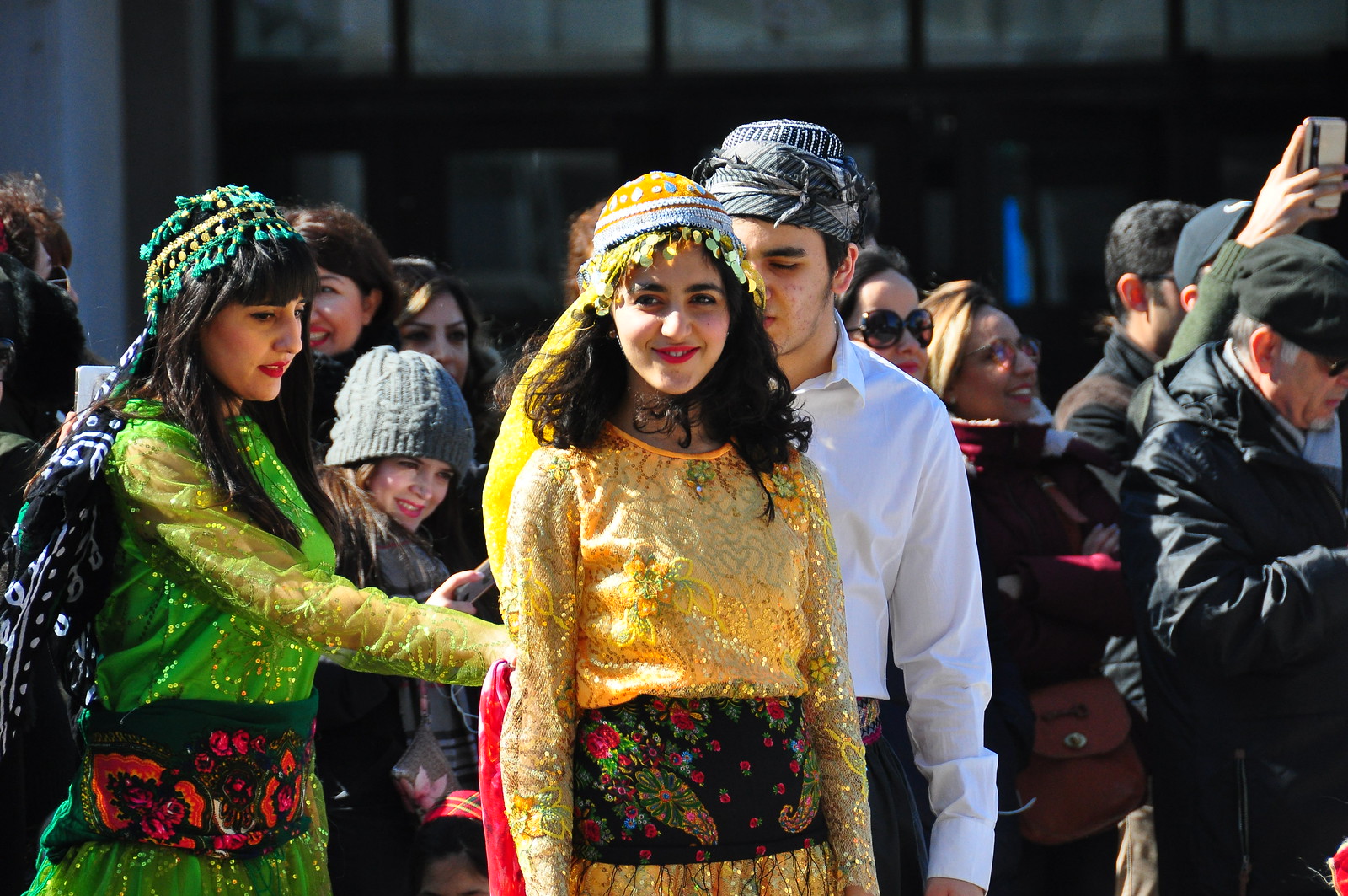 Norouz 2018 Trois artistes devant une foule. L'une d'elles est vêtue d'une tenue jaune doré et sourit à la caméra.