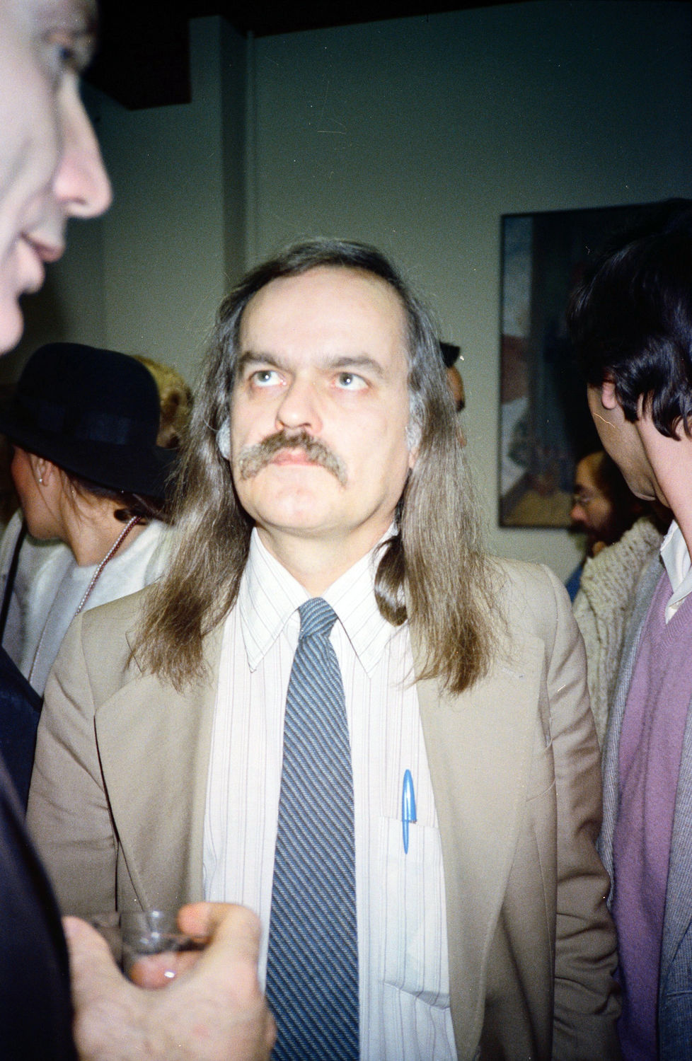 A man with long hair and a mustache in a crowd.