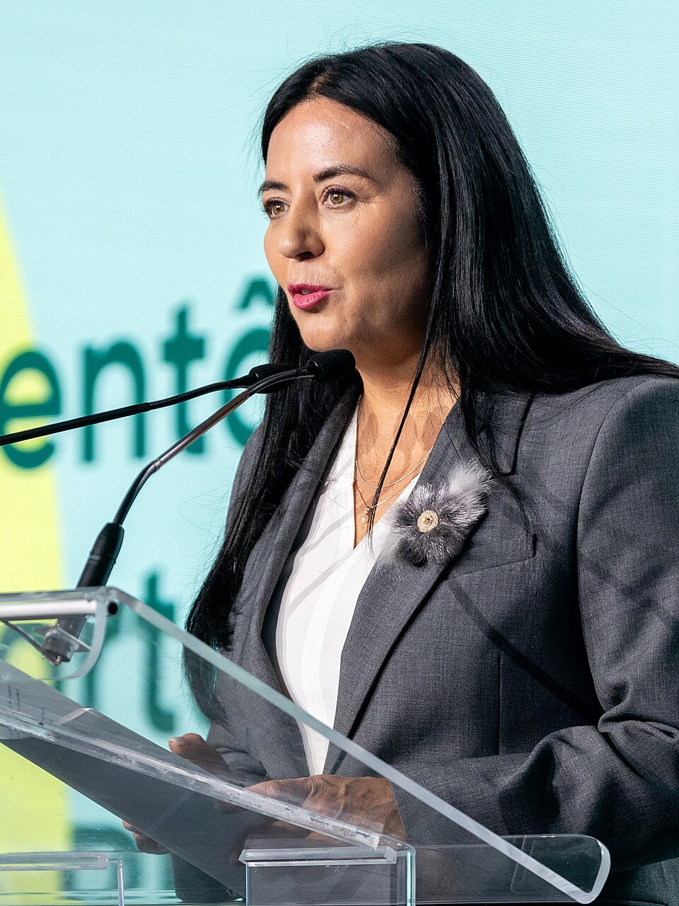 Une femme aux cheveux noirs à un podium.