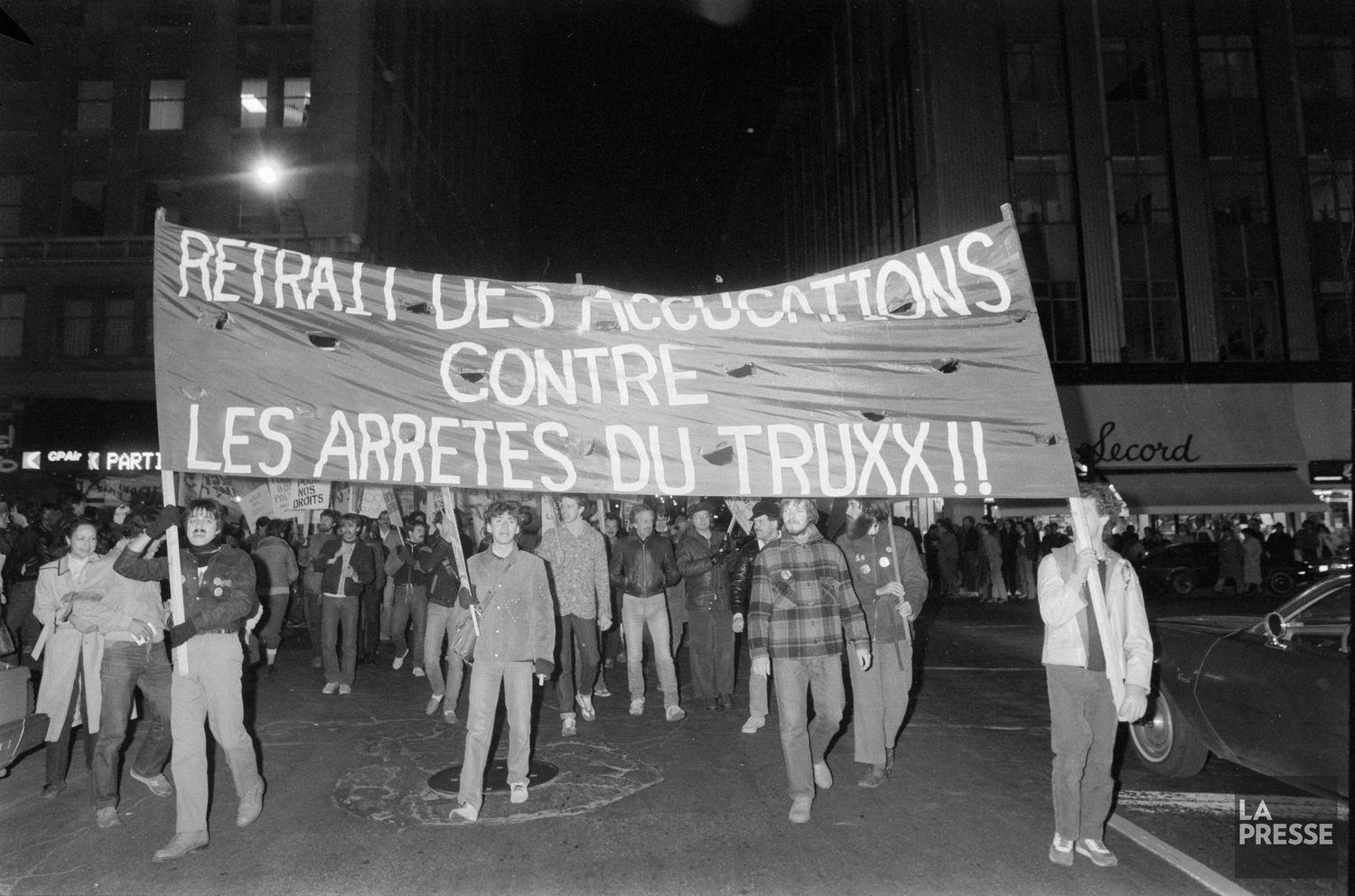 Protesters holding a banner advocating for those arrested during the Truxx police raid.