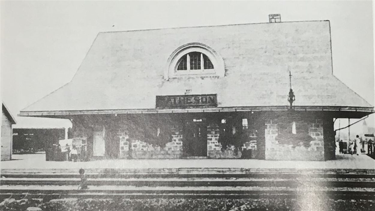 Black-and-white old image of small train station.