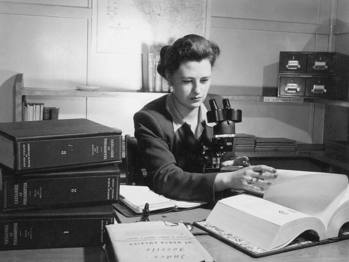 Diane Loranger travaille à un bureau avec des livres et un microscope.