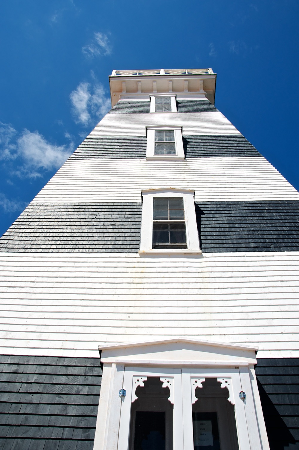 Photographie en contre-plongée du phare avec ses rayures noires et blanches.