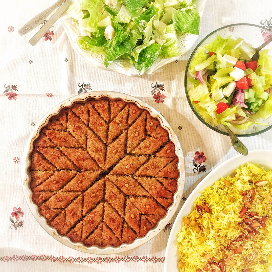 Baked kibbeh besides rice and salad dishes