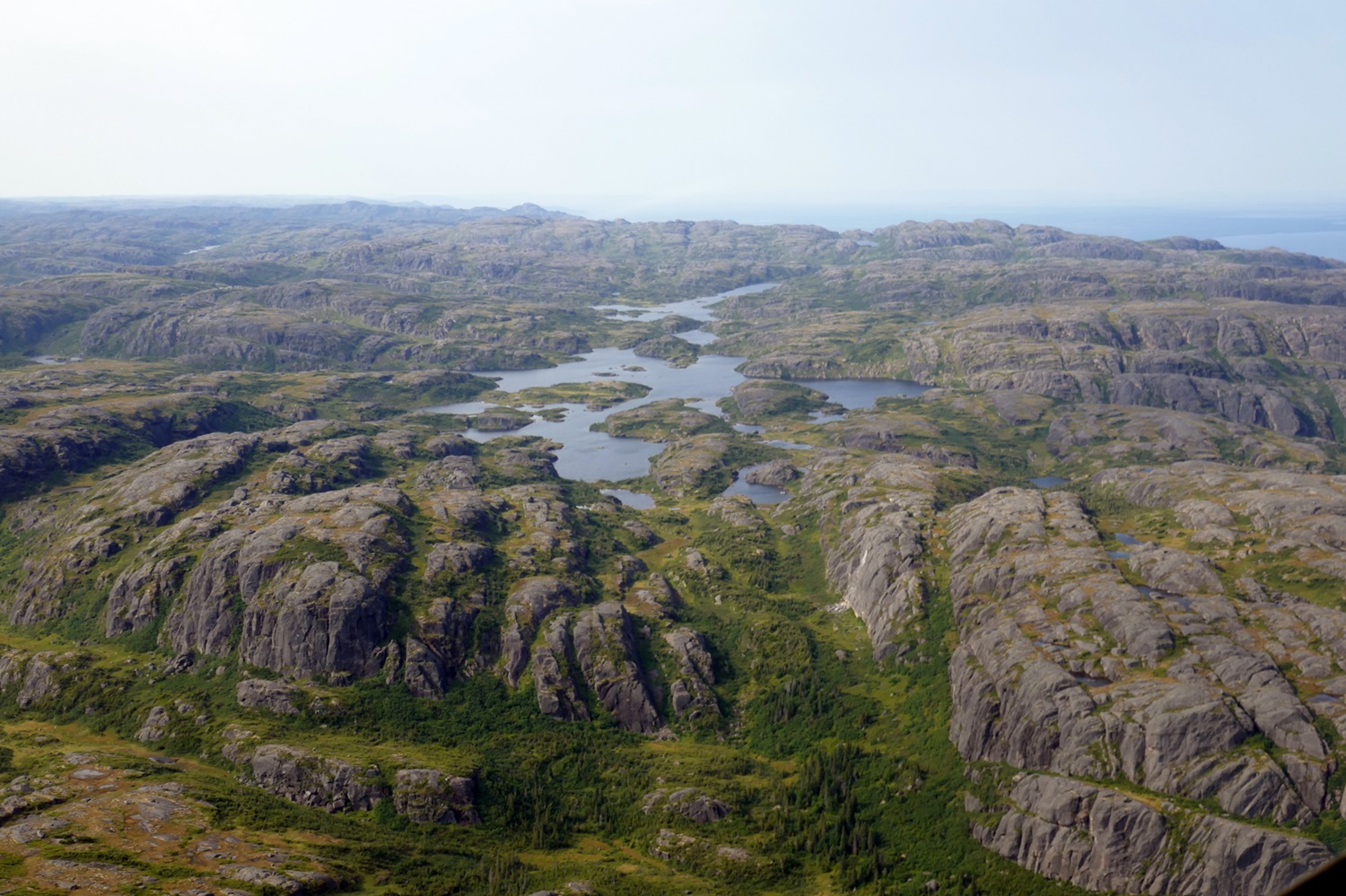 Terrain rocheux et montagneux avec quelques lacs et conifères dans les basses terres.