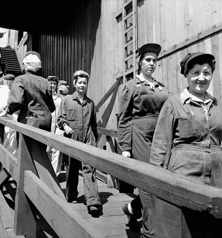 Female shipyard workers walking down a path returning to work after a 30-minute lunch break in the shipyard cafeteria, May 1943.