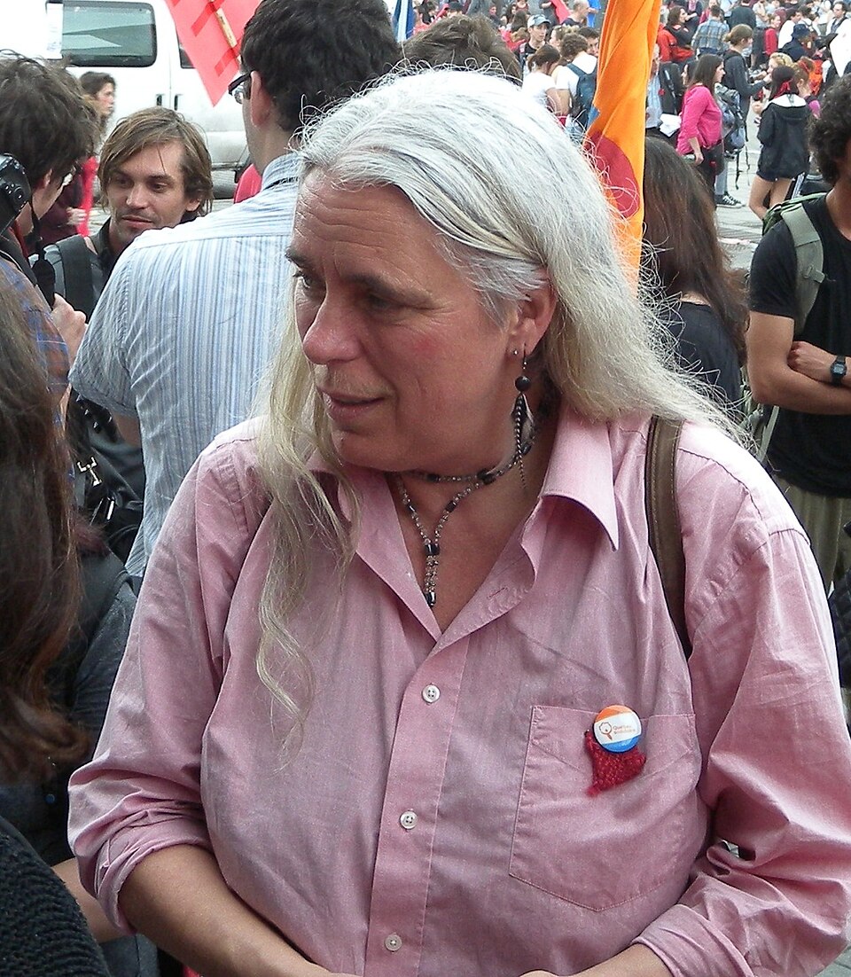 Manon Massé (2012) Manon Massé dans une foule, vêtue d'un chemise rose.