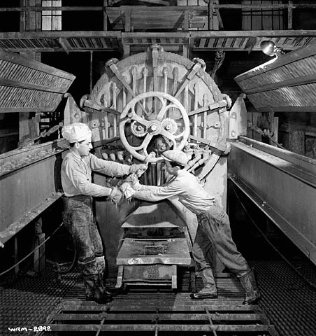 Workers at the Aluminum Company of Canada in Arvida, Quebec, tighten a press, January 1943.